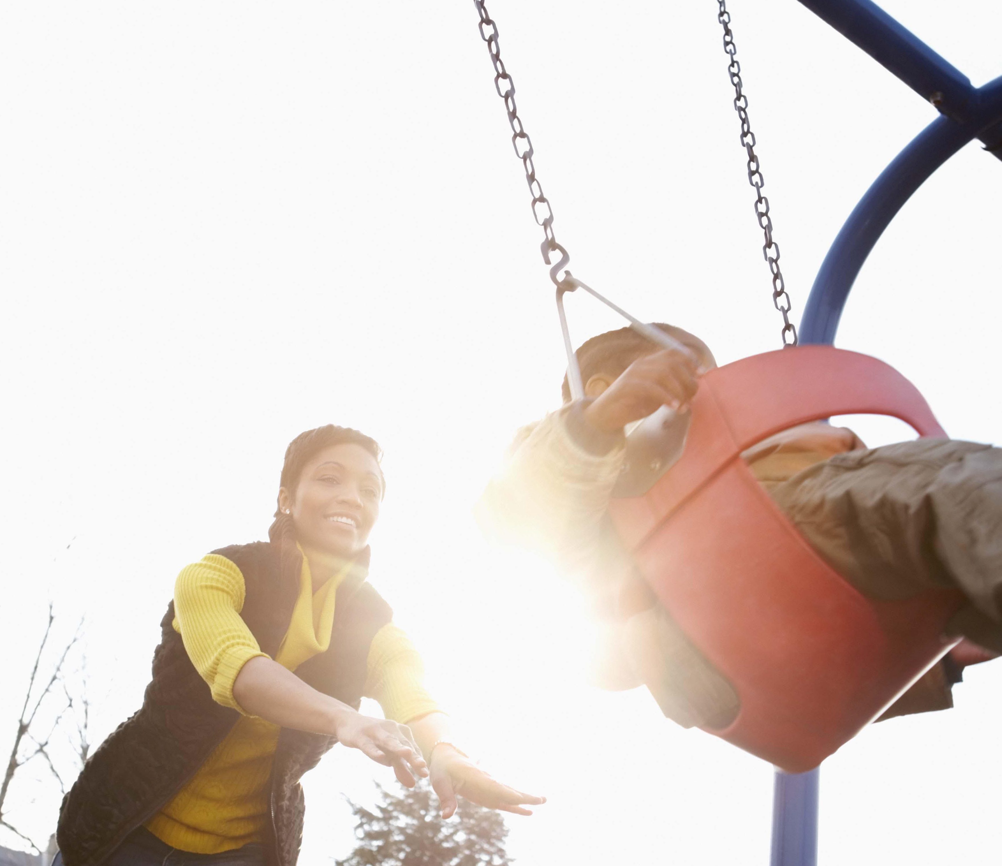 Mother pushing child on swingset