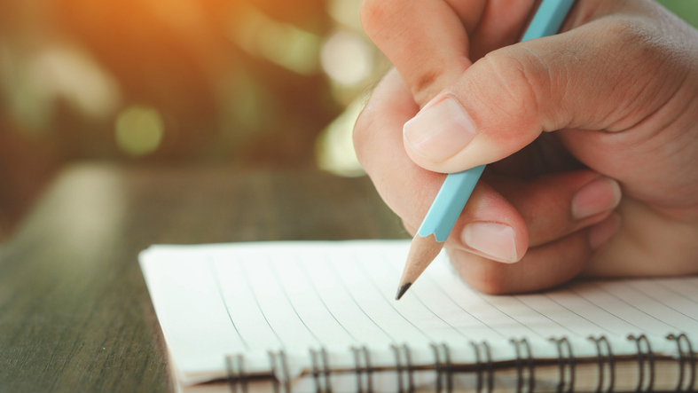 Man hand with pencil writing on notebook. focus on man hand holding pen